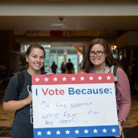 Student holding sign titled "I vote because: Of the women who fought for the opportunity"